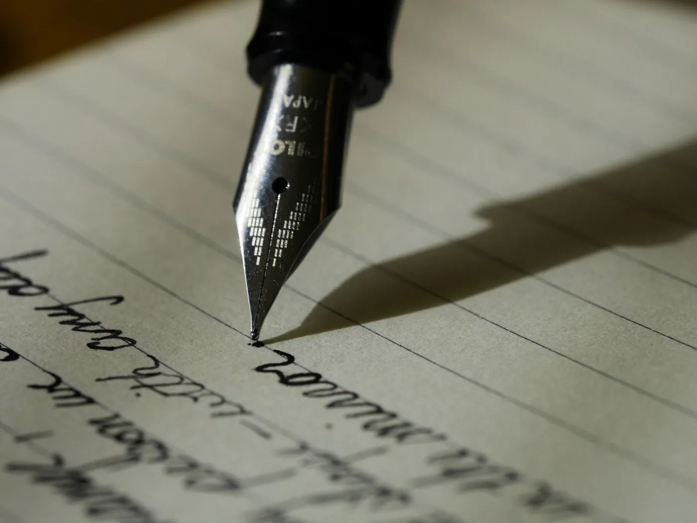 Detalle de una pluma escribiendo en una página de cuaderno