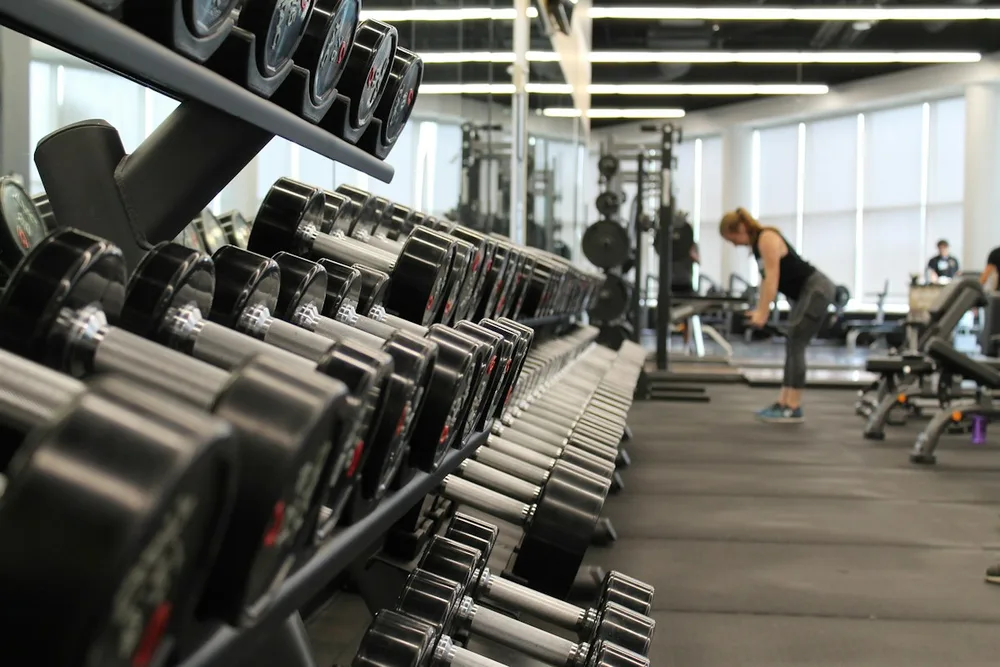 Zona de entrenamiento con material de fuerza y grandes ventanales