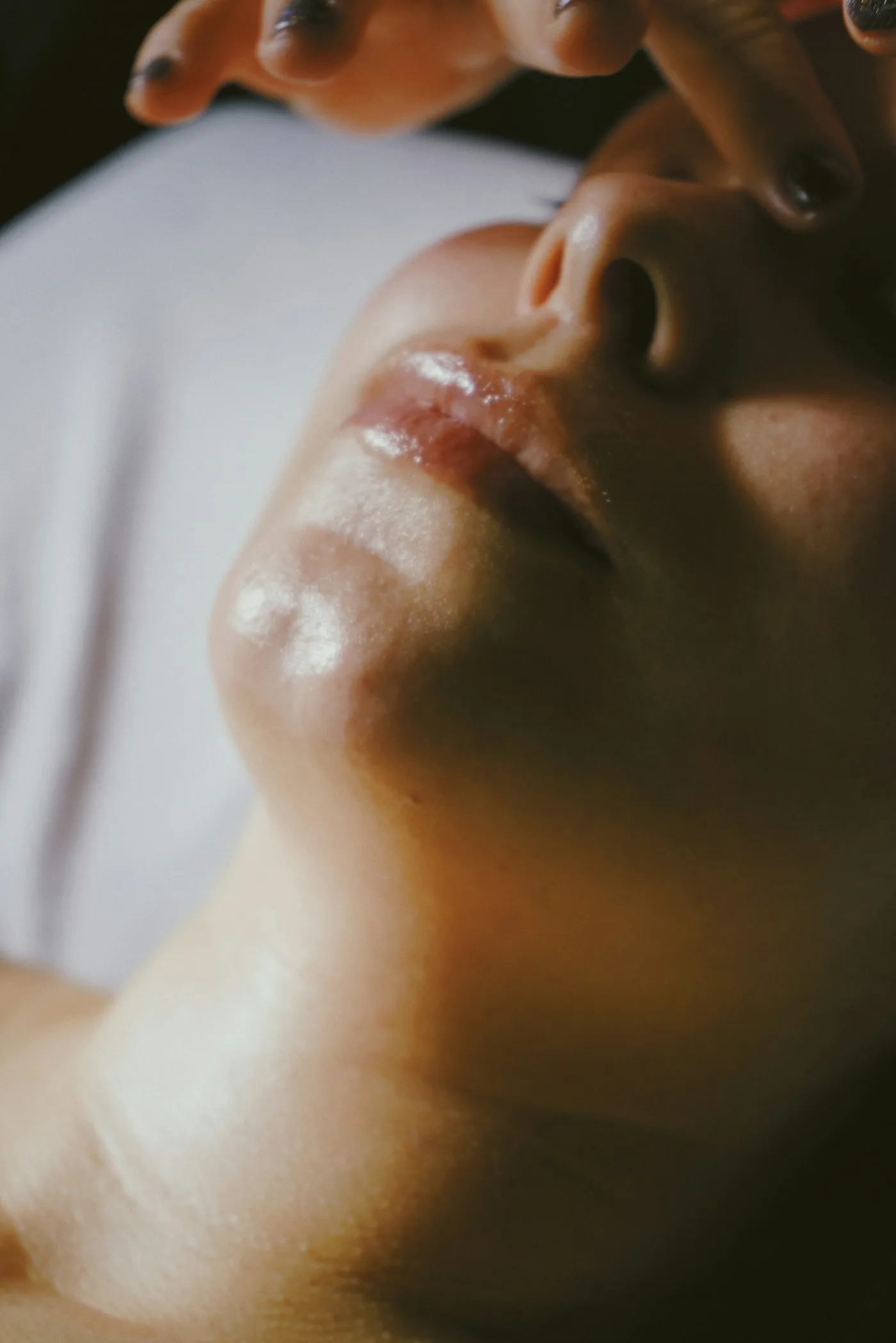 Manos de esteticista acompañando un masaje facial, con luz cálida sobre la piel